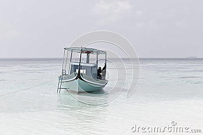 Ari Atoll, Maldives: A maldivian sailor is fishing on his blue boat called `dhoni` Editorial Stock Photo