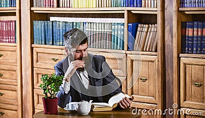 Aristocrat on thoughtful face reading book. Oldfashioned man near cup Stock Photo