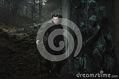 Aristocratic vampire leaning to graveyard statue Stock Photo