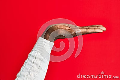 Arm and hand of african american black young man over red isolated background with flat palm presenting product, offer and giving Stock Photo