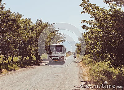 Armenian bus and a guy in a bike in a small road without fence and trees Editorial Stock Photo