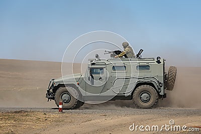 Armored car GAZ-233014 Tiger with a machine gunner upstairs quickly goes on a military training ground Editorial Stock Photo