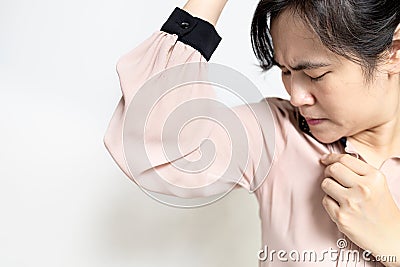 Armpit smelly or the body odor foul,Upset asian lady woman sniffing her wet armpit,smelling something stinks,body stench and sweat Stock Photo