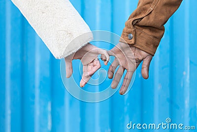 Arms of interracial couple holding hands, great love symbolic concept, blue background Stock Photo