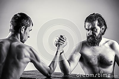 Arms wrestling thin hand, big strong arm in studio. Two man`s hands clasped arm wrestling, strong and weak, unequal Stock Photo