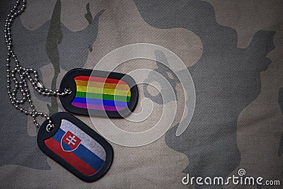 army blank, dog tag with flag of slovakia and gay rainbow flag on the khaki texture background. Stock Photo