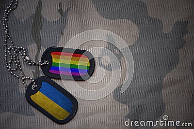 army blank, dog tag with flag of ukraine and gay rainbow flag on the khaki texture background. Stock Photo