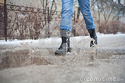 Go army boots through puddles in the city, black lace-up boots and wet weather, trekking shoes in the city, rain, snow, and hail i Stock Photo