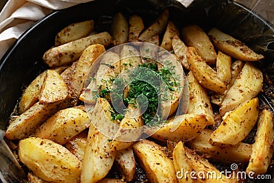 Aromatic baked potato wedges with fresh dill herbs. Homemade rustic dish, delicious hearty food close up Stock Photo