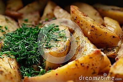 Aromatic baked potato wedges with fresh dill herbs. Homemade rustic dish, delicious hearty food close up Stock Photo