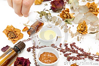 Aromatic botanical cosmetics. Dried herbs flowers mixture, facial mud clay mask, oils, applying brush. Holistic herbal skincare Stock Photo