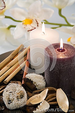 Aromatic candles burn on a dish with an orchid Stock Photo