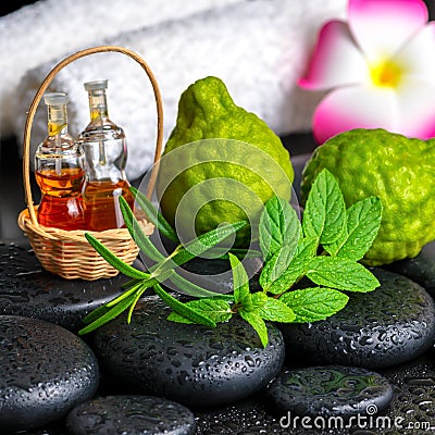 Aromatic concept of bergamot fruits, fresh mint, rosemary, candles, towels, flower and bottles essential oil on zen stones Stock Photo