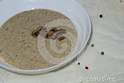 Aromatic mushroom cream soup with champignons. Fresh vegetables and freshly baked bread. A hearty and delicious lunch. Stock Photo