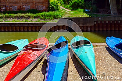 Arranged red and blue kayaks on the concrete coast by the river Stock Photo