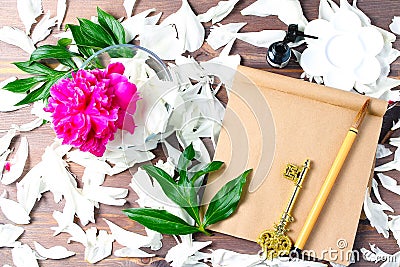 Arrangement of fresh petals of peonies and flowers, a notebook and a brush for lettering. dark wooden background, view from the Stock Photo