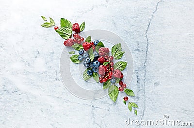 An Arrangement of fresh raspberries, blueberries, red currant and mint leaves on gray marble background. Stock Photo