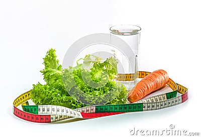 Carrot, green salad leaves and a glass of water surrounded by a measuring tape. Weight loss Stock Photo