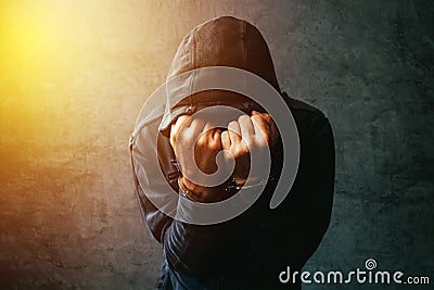 Arrested computer hacker with handcuffs wearing hooded jacket Stock Photo