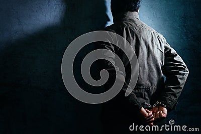 Arrested male criminal with handcuffs facing prison wall Stock Photo