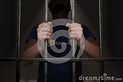 Arrested prisoner is holding bars in prison cell Stock Photo