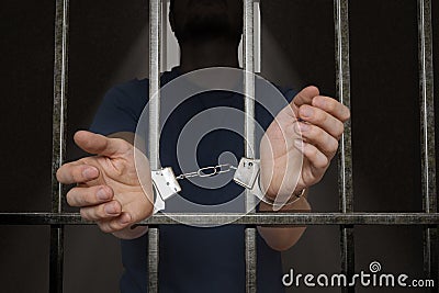 Arrested prisoner is holding bars in prison cell Stock Photo