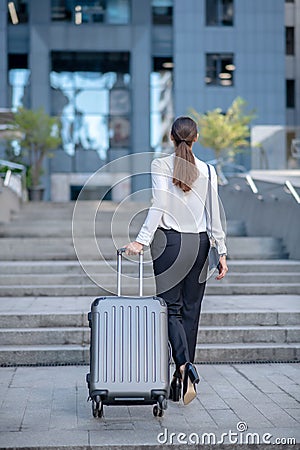 Tall brunette woman carrying her big suitcase Stock Photo