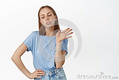 Arrogant blond girl wave hand and looking away ignorant, skip smth, disagree, refusing offer, rejecting or declining Stock Photo