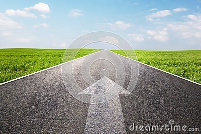 Arrow sign pointing forward on long empty straight road Stock Photo