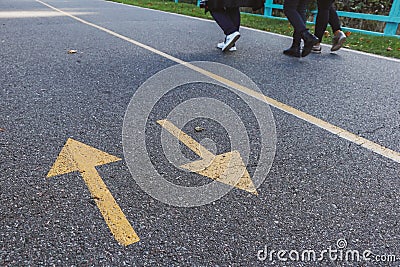 Arrows road sign painted with yellow paint on asphalt on bike path Stock Photo