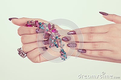 Art Manicure. Modern style burgundy vinous velvet effect Nail Polish. Stylish Nails beauty hands holding magenta blue green broach Stock Photo