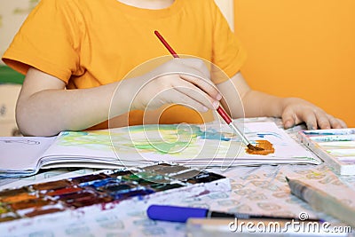 art painting, childrens hands holding brush and drawing of orange paint Editorial Stock Photo