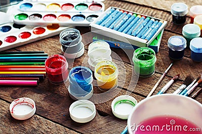 Art of Painting. Paint buckets on wood background. Different paint colors painting on wooden background. Painting set: brushes, pa Stock Photo