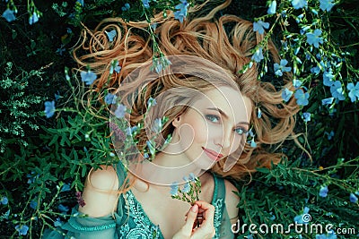 Art photo fairy tale beauty. Portrait Fantasy woman lies on blooming meadow in blue vintage dress. Summer nature Stock Photo