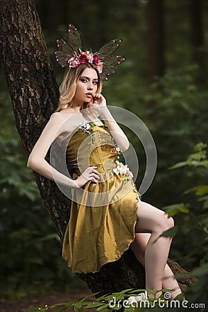 Art Photography. Young Beautiful Girl Posing With Artistic Butterfly Head Gear and Light Flowery Dress In Forest Stock Photo