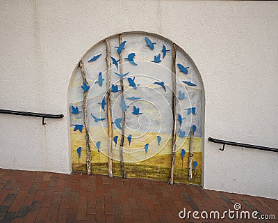 Art piece along a Vail, Colorado shopping street that features blue steel birds, linear pieces of wood and a painted landscape. Editorial Stock Photo