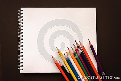 Art Sketchpad Colored Pencils on brown background, back to school concept. School accessories, space or text flat lay Stock Photo