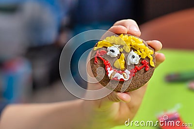 Art work done by a child. A cinnamon round cookie decorated by a child. A smiling face painted with colorful iced felt-tip pens. Stock Photo