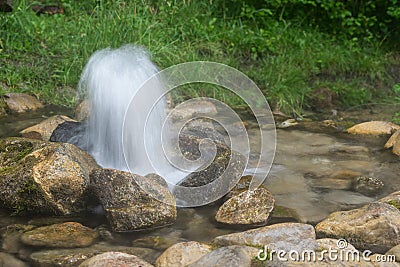 Artesian well. Eruption of spring, natural environment. Stones and water. Clean drinking groundwater erupting out of the ground. Stock Photo