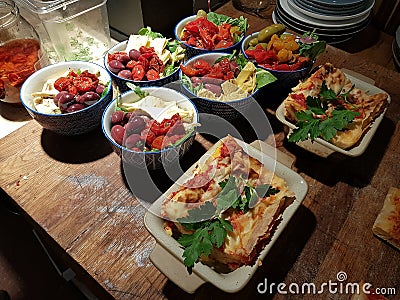 Artichokes, cherry tomatoes and olives with olive oil and salad and vegetarian lasagna. Stock Photo