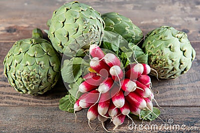 Artichokes and radishes on wooden table Stock Photo