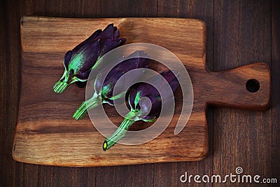 Artichokes, small, violet on a cutting board Stock Photo