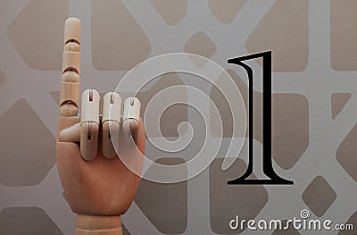 Articulated wooden hand with a finger raised in allusion to number one Stock Photo