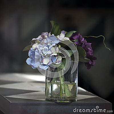 The artificial bouquet of pink and purple hydrangeas on a table in a cafe. The sun gives shadows Stock Photo