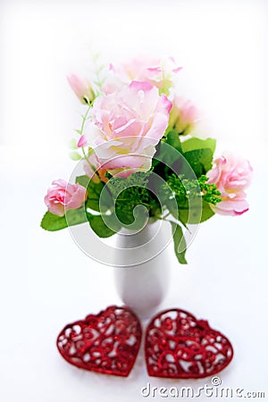 Artificial flower and white vase on white background, decoration with red hearts, wedding interior detail close up Stock Photo