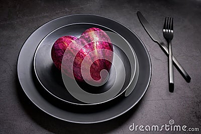 Artificial heart on a black plate Stock Photo