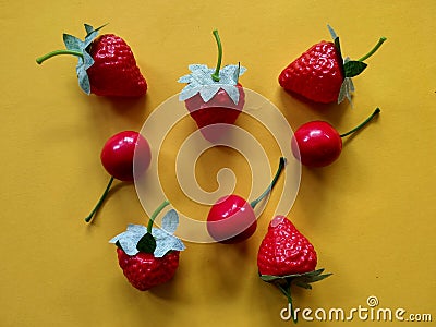 Artificial strawberries and cherries fruit isolated on orange background Stock Photo