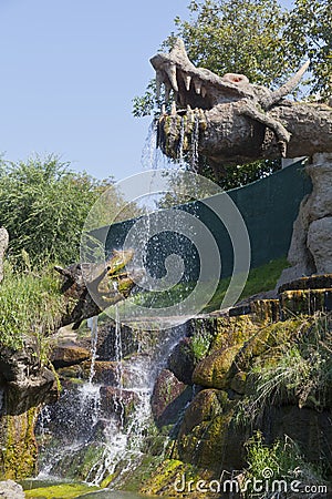 Artificial waterfall from the mouth of a huge dragon decorative composition made from stone and concrete Editorial Stock Photo