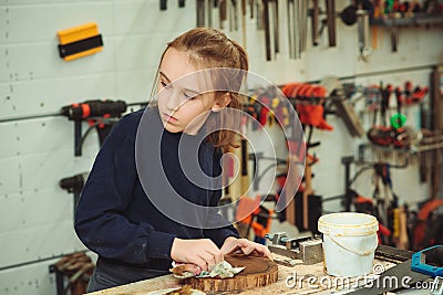 Artisan boy is putting a protective mordant on the wood. Cute boy makes wooden clock in the workshop Stock Photo