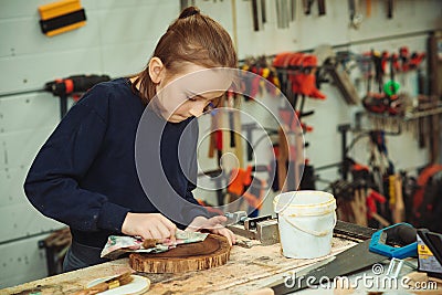 Artisan boy is putting a protective mordant on the wood. Cute boy makes wooden clock in the workshop Stock Photo